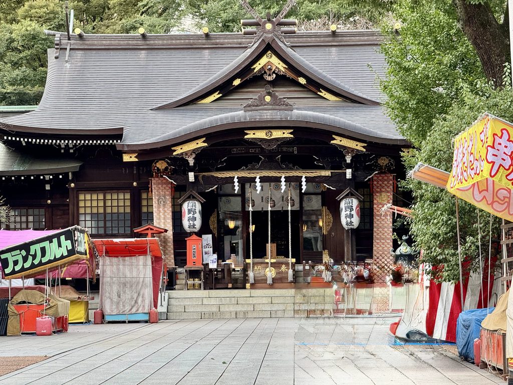 十二社熊野神社の鳥居越しに見る拝殿と、例大祭を控えて準備が進む境内の様子