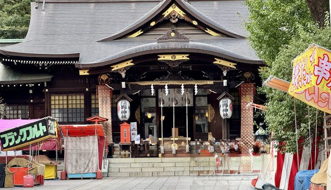 十二社熊野神社の鳥居越しに見る拝殿と、例大祭を控えて準備が進む境内の様子