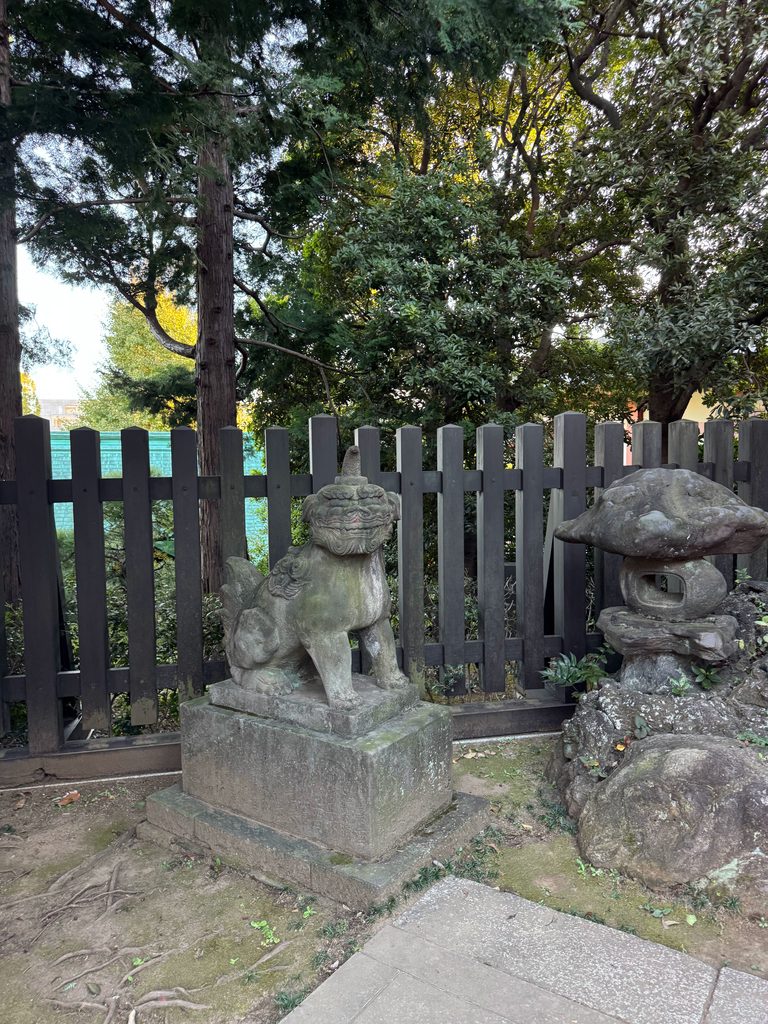 穴八幡宮の参道脇に鎮座する苔むした歴史ある古い石造狛犬と灯籠